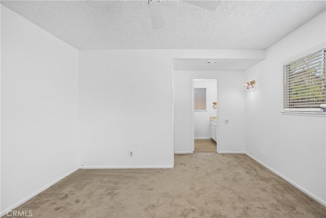 spare room featuring a ceiling fan, a textured ceiling, baseboards, and carpet