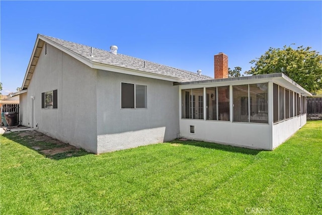back of house with roof with shingles, stucco siding, a chimney, a sunroom, and a yard