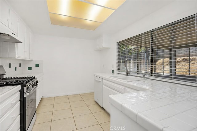 kitchen featuring decorative backsplash, white dishwasher, a sink, stainless steel gas range, and tile counters