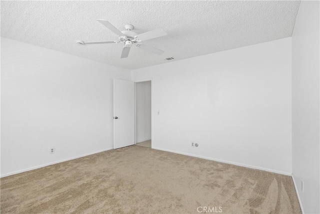 carpeted spare room with baseboards, ceiling fan, a textured ceiling, and visible vents