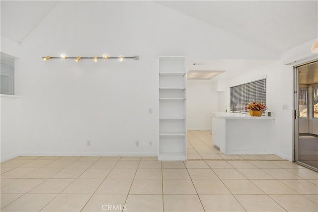 unfurnished room featuring light tile patterned flooring, high vaulted ceiling, and baseboards