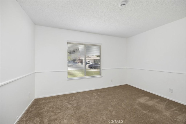 carpeted spare room with a textured ceiling and baseboards
