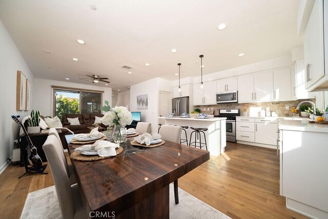 dining space featuring light wood-style floors, a ceiling fan, recessed lighting, and visible vents