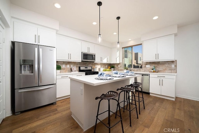 kitchen featuring appliances with stainless steel finishes, white cabinets, backsplash, and dark wood-style floors