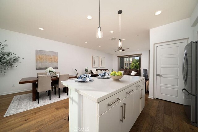 kitchen featuring light countertops, white cabinets, freestanding refrigerator, and dark wood-style floors