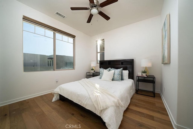 bedroom with baseboards, wood finished floors, and visible vents