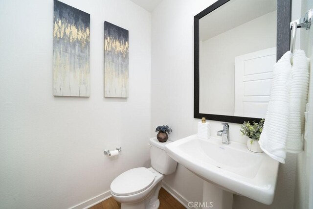 bathroom with a sink, baseboards, toilet, and wood finished floors