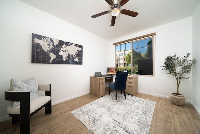 office with light wood-style floors, a ceiling fan, and baseboards