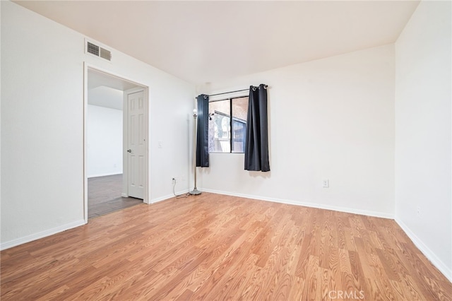 spare room featuring visible vents, light wood-style flooring, and baseboards