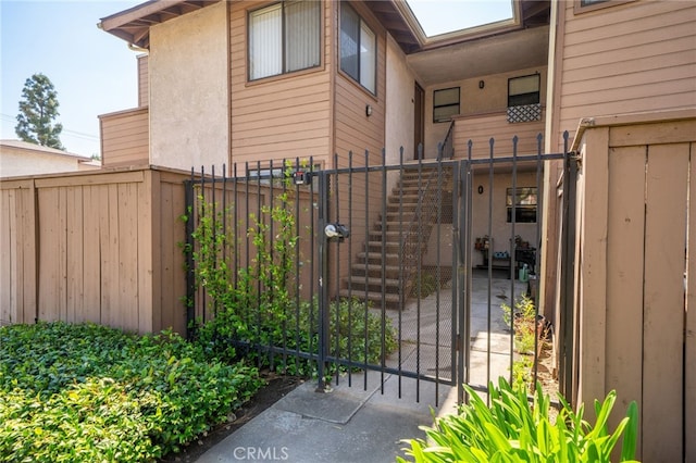 view of gate featuring fence and stairway