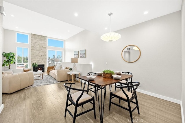 1310 N Detroit St Unit 405, Los Angeles, CA 90046 - dining area with baseboards, light wood-style flooring, a high ceiling, and a fireplace