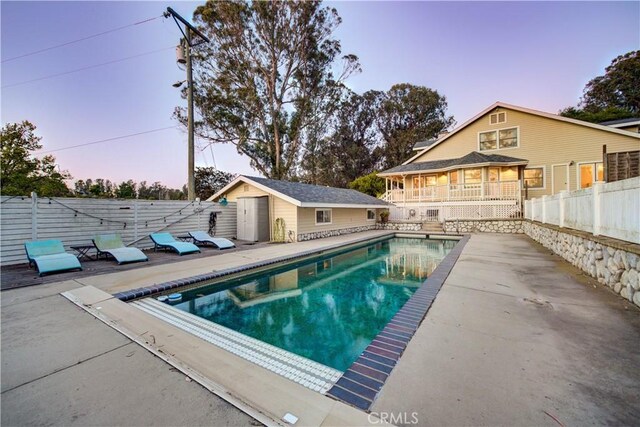 view of pool featuring a patio, fence, an outbuilding, and a fenced in pool