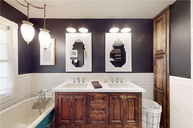 full bathroom featuring a sink, tile walls, and a freestanding bath