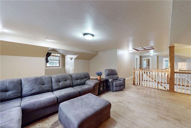 living room with baseboards, vaulted ceiling, and light wood finished floors
