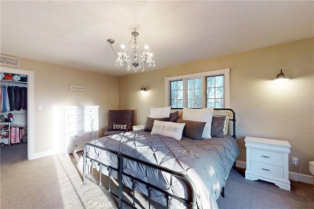 carpeted bedroom featuring a walk in closet, baseboards, a closet, and a notable chandelier