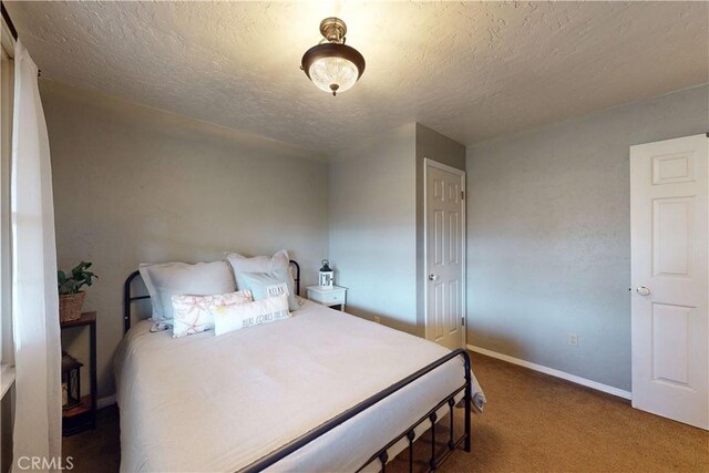 carpeted bedroom with baseboards and a textured ceiling