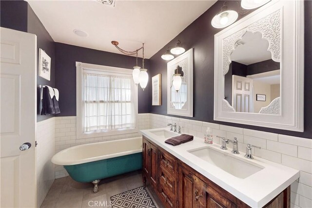 bathroom with a sink, tile walls, tile patterned flooring, and a freestanding bath