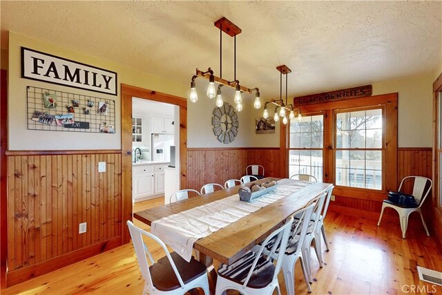 dining space featuring wood walls, wainscoting, and light wood finished floors