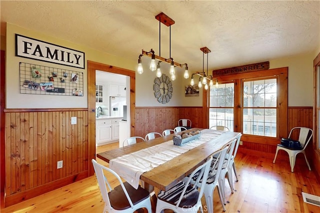1473 Willow Rd, Nipomo, CA 93444 - dining area with wainscoting, wooden walls, light wood-type flooring, and a textured ceiling