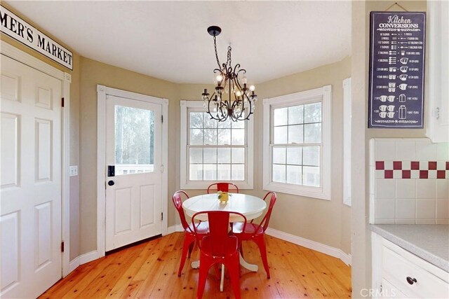 dining area with an inviting chandelier, baseboards, and light wood-type flooring