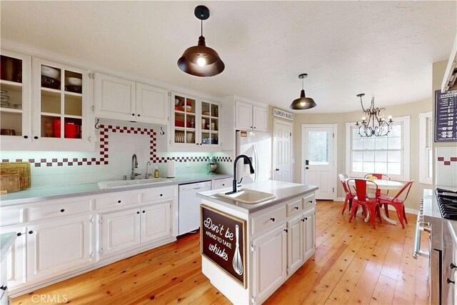 kitchen with an inviting chandelier, a sink, backsplash, and white appliances