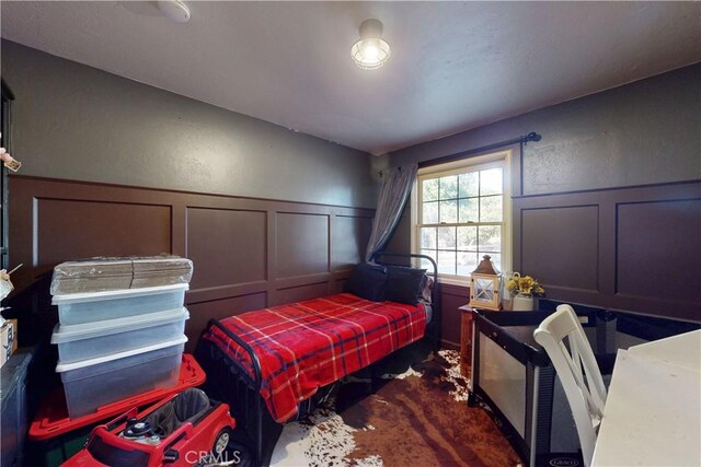 bedroom featuring a wainscoted wall and a decorative wall