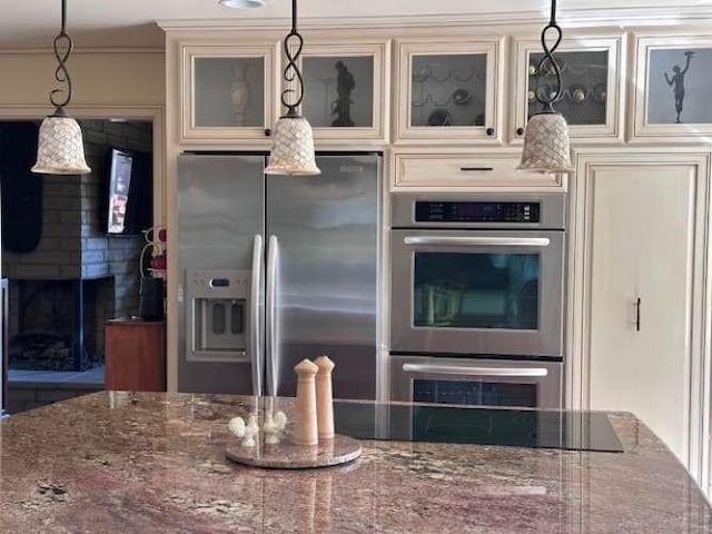 61 Paseo Esplendido, Camarillo, CA 93010 - kitchen featuring pendant lighting, a fireplace, glass insert cabinets, dark stone counters, and stainless steel appliances
