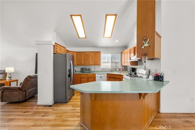27828 Spyglass Ln, Canyon Country, CA 91351 - kitchen featuring light wood-type flooring, a peninsula, vaulted ceiling, and white appliances