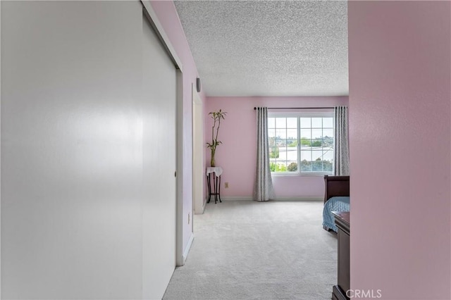 hall featuring a textured ceiling, carpet floors, and baseboards