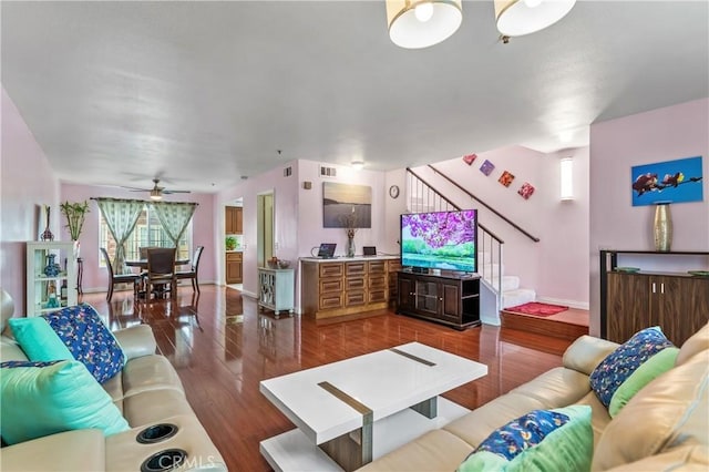 living room with baseboards, visible vents, ceiling fan, stairs, and wood finished floors