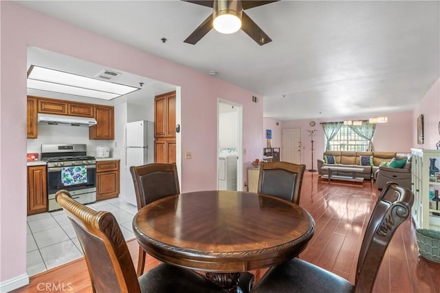 dining space featuring washing machine and clothes dryer, visible vents, light tile patterned flooring, and ceiling fan
