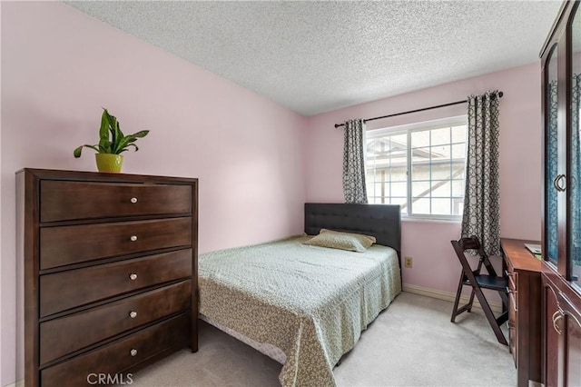 bedroom with light colored carpet, a textured ceiling, and baseboards