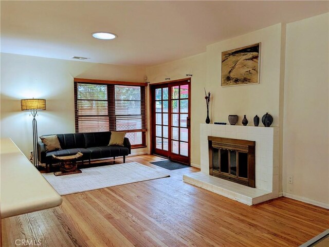 living area featuring visible vents, wood finished floors, a wealth of natural light, and a fireplace
