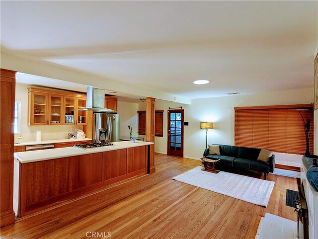 living area with baseboards, decorative columns, and light wood-type flooring