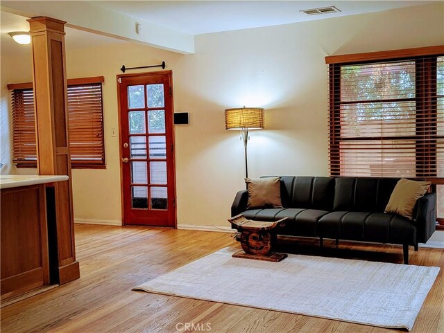 living room with baseboards, visible vents, plenty of natural light, and light wood-style floors