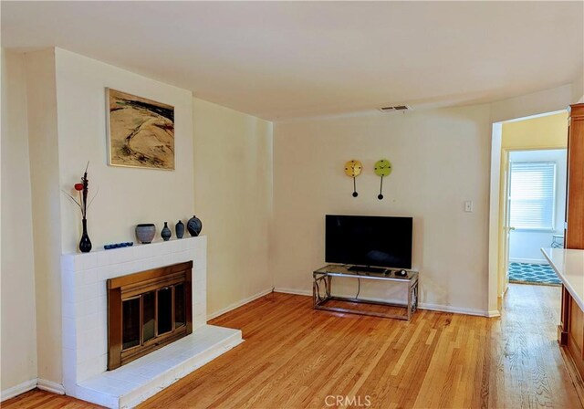 living room featuring baseboards, a tile fireplace, and light wood-style floors