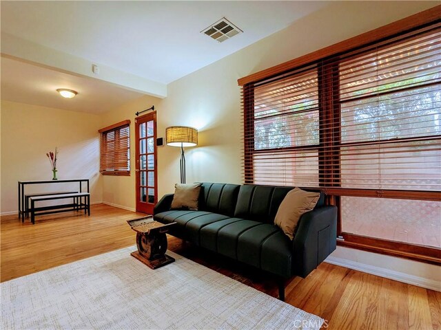 living room with baseboards, visible vents, and wood finished floors