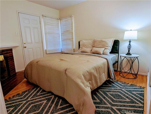 bedroom with baseboards, wood finished floors, and a fireplace