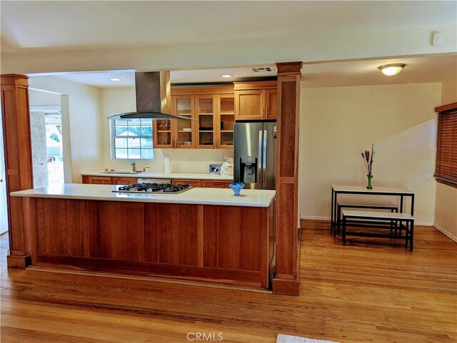 kitchen featuring light wood-style flooring, appliances with stainless steel finishes, brown cabinets, and island range hood