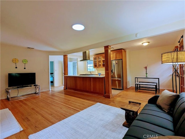 living room with baseboards, light wood-type flooring, ornate columns, and visible vents