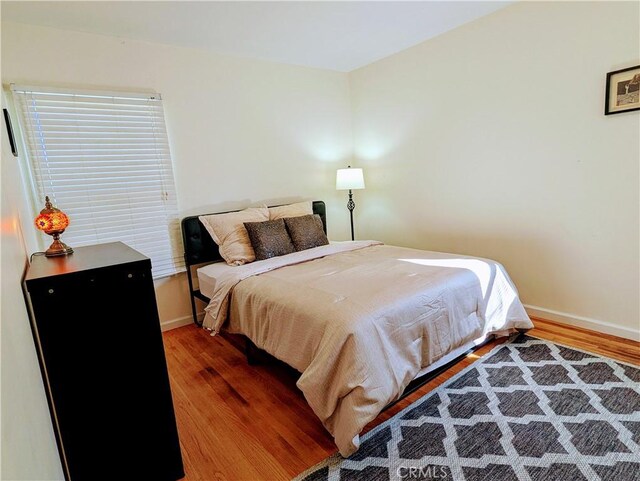 bedroom with baseboards and wood finished floors
