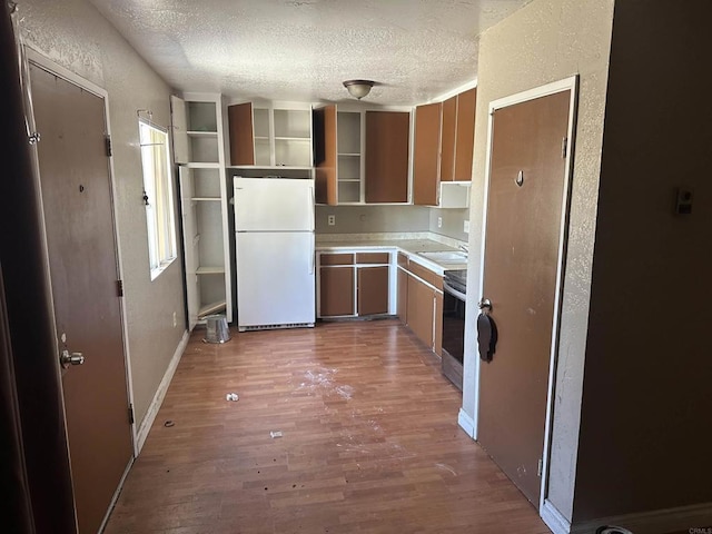 kitchen featuring freestanding refrigerator, a textured ceiling, stainless steel electric stove, and wood finished floors