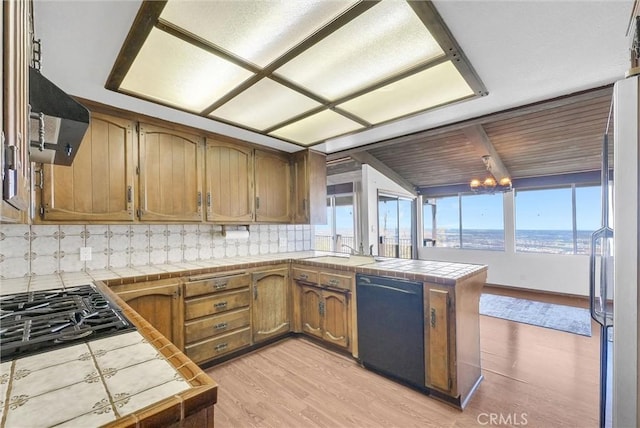 30062 Grandpoint Ln, Rancho Palos Verdes, CA 90275 - kitchen with black appliances, tile counters, a peninsula, decorative backsplash, and extractor fan