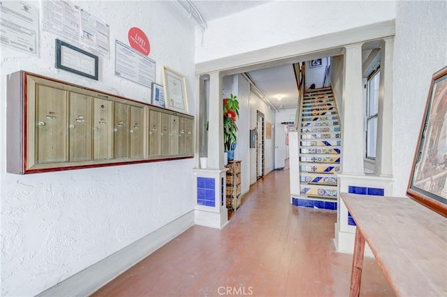 corridor with stairs, a textured wall, and mail area