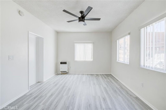 unfurnished living room featuring ceiling fan, a textured ceiling, heating unit, and wood finished floors
