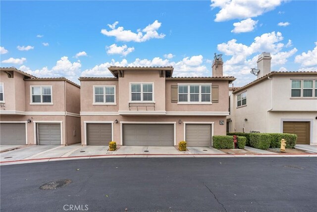 15427 Park Point Ave Unit 110, Lake Elsinore, CA 92532 - view of property with stucco siding, an attached garage, a chimney, and a tile roof