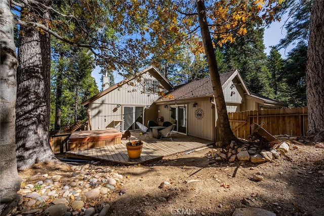 rear view of property with fence, a covered hot tub, and a deck