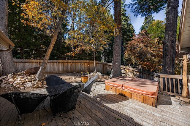 wooden deck featuring a covered hot tub and a fenced backyard