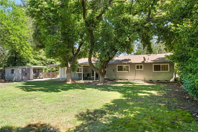 9137 Midway, Durham, CA 95938 - rear view of house featuring fence, stucco siding, a storage unit, an outbuilding, and a yard