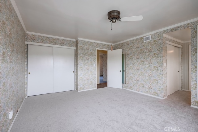 unfurnished bedroom with visible vents, crown molding, carpet floors, a closet, and wallpapered walls